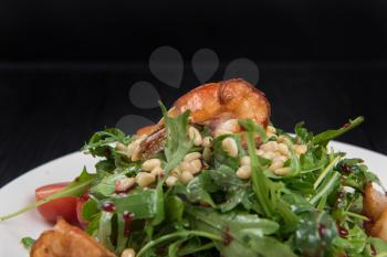 Green salad with shrimps: greens, arugula, tomato, pine nuts and sauce