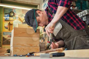 Carpenter working with a chisel and hammer in a wooden workshop. Profession, carpentry and manual woodwork concept.