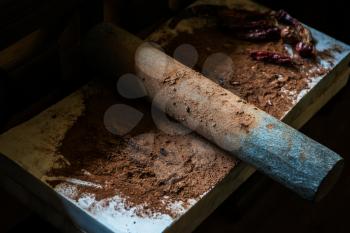 Grinding cacao beans with chili peppers to make chocolate by stone rolling pin on stone surface. hand made chocolate.