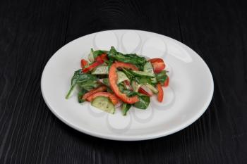 Fresh vegetable salad of cucumbers, tomatoes, raddish, bell pepper, basil and olive oil.