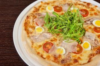 meat pizza with chicken, rukkola and eggs at the table