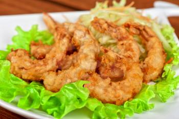 Fried shrimps with lettuce at white plate