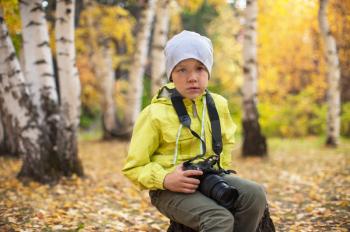 Baby boy with camera in autumn forest