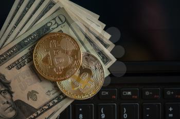 Bitcoin coins with dollars on the laptop background
