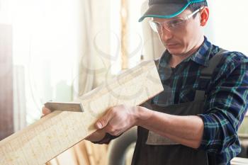 The worker makes measurements of a wooden board with corner ruler. Profession, carpentry and woodwork concept.