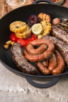 Grilled different meat sausages with vegetables and spices