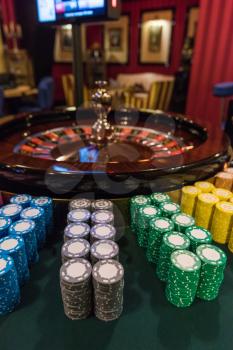 Casino, gambling and entertainment concept - roulette table and stack of poker chips