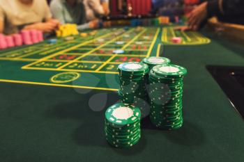 Casino, gambling and entertainment concept - stack of poker chips on a green table