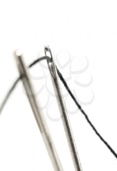 Two needles with thread over white, focused on the back (shallow DOF)
