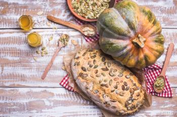 Newly baked bread with seeds and pumpkin on wooden table. Rustic style food photo