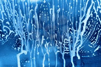 Bright blue abstract texture with soap foam on glass