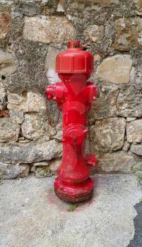 Red old fireplug against a stone wall background