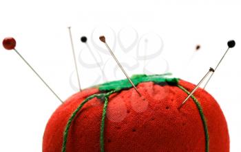 Royalty Free Photo of a Pins Stuck in a Pin Cushion Shaped Like a Tomato