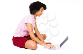 Smiling teenage girl using a laptop isolated over white