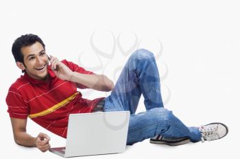 Man talking on a mobile phone while using a laptop