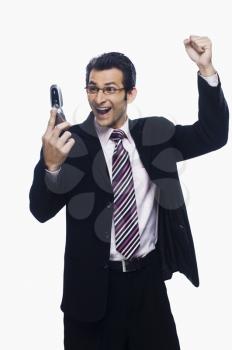 Businessman clenching fist while reading a text message on a mobile phone