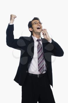 Businessman clenching fist while talking on a mobile phone