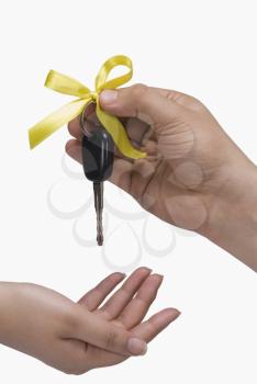 Close-up of a person's hand giving a car key to another person