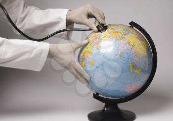 Close-up of a person's hands examining a globe with a stethoscope