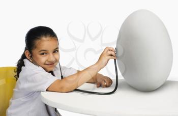 Girl examining a egg with a stethoscope