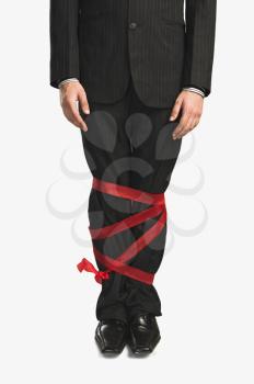 Businessman's legs tied up with a ribbon