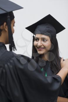 Woman in graduation gown smiling at her friend