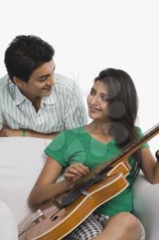Woman playing a guitar beside his boyfriend