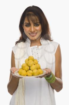 Woman holding Laddu in a plate on Holi