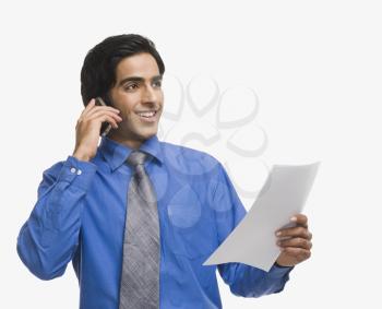 Businessman talking on a mobile phone and holding a document