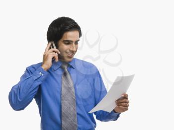 Businessman talking on a mobile phone while reading a document