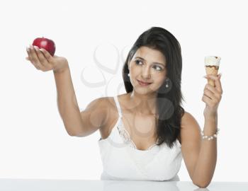 Woman comparing an ice cream cone with an apple