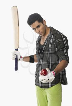 Portrait of a cricket player holding a ball and bat