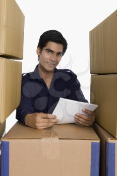 Store incharge holding papers with cardboard boxes