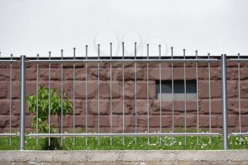 Small iron and transparent fence on the background of a residential building