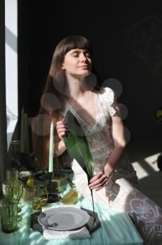 Young girl with an aspidistra leaf next to a window and harsh sunlight.