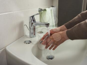 Unrecognisable man carefully washing hands at home for health safety