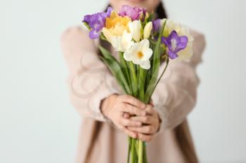 Little girl with bouquet of flowers on light background�