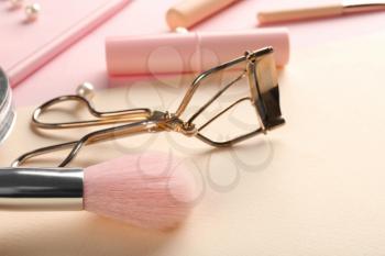 Brush for applying makeup and eyelash curler on color background, closeup�