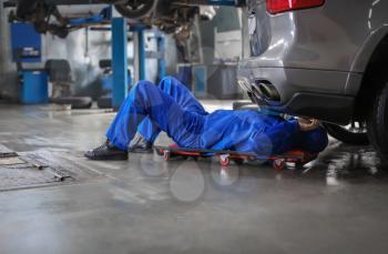 Male mechanic fixing car in service center�