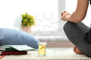 Cup of white tea near woman practicing yoga indoors�