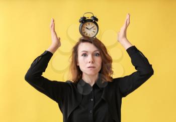 Mature woman with alarm clock on head against color background. Time management concept�