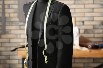 Tailor's mannequin with half-finished jacket and measuring tape in atelier�