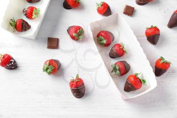 Delicious strawberries covered with chocolate on white wooden table�