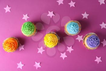 Delicious birthday cupcakes on color background�