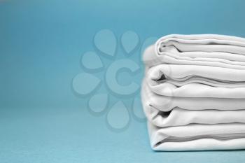 Stack of clean bed sheets on color background�