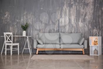 Interior of living room with stylish comfortable sofa near wall�