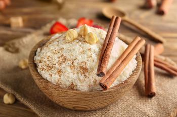 Delicious rice pudding with cinnamon and hazelnuts in bowl on wooden table�