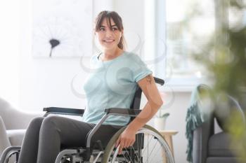 Happy young woman in wheelchair at home�