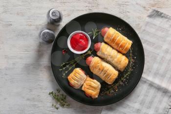 Plate with tasty sausage rolls and sauce on wooden table�