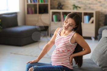 Young pregnant woman suffering from pain at home�